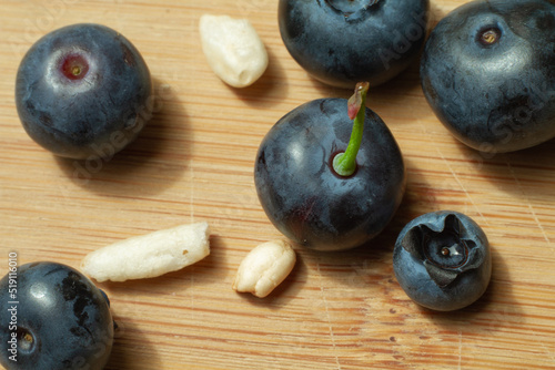 blue berries with some seeds of puffed rice on the bamboo cutting board