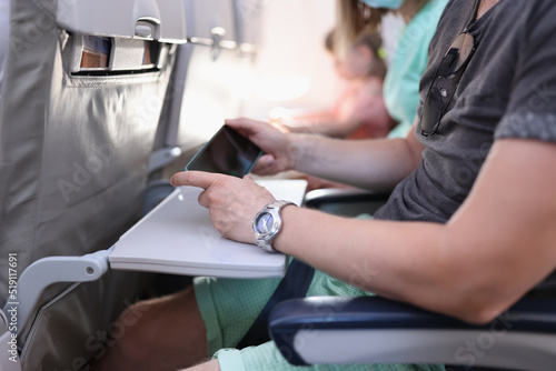 Man hands with a smartphone sits in cabin of airplane or train