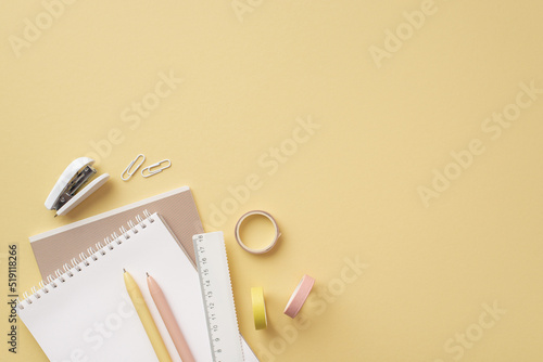 School accessories concept. Top view photo of school supplies notepads ruler pens clips mini stapler and adhesive tape on isolated pastel yellow background with copyspace
