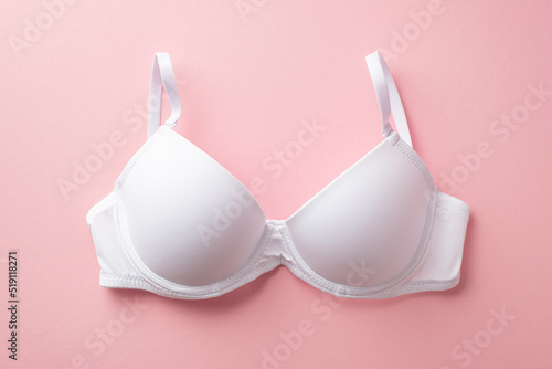 Breast cancer awareness concept. Top view photo of white brassiere on isolated pastel pink background