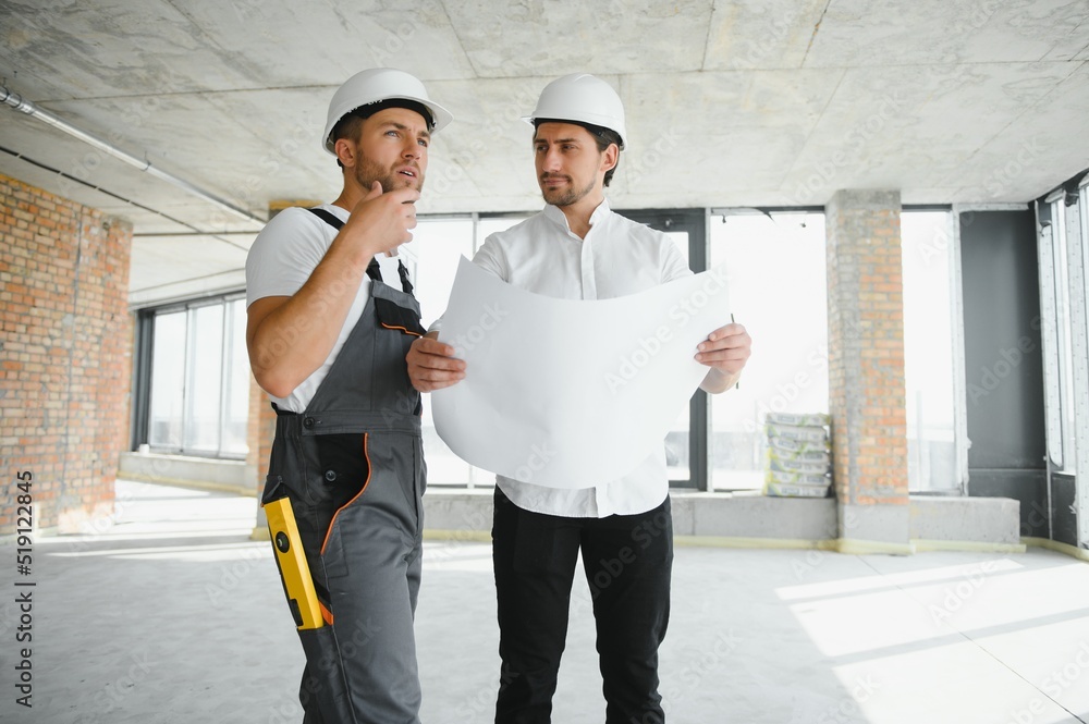 Male Architect Giving Instructions To His Foreman At Construction Site.