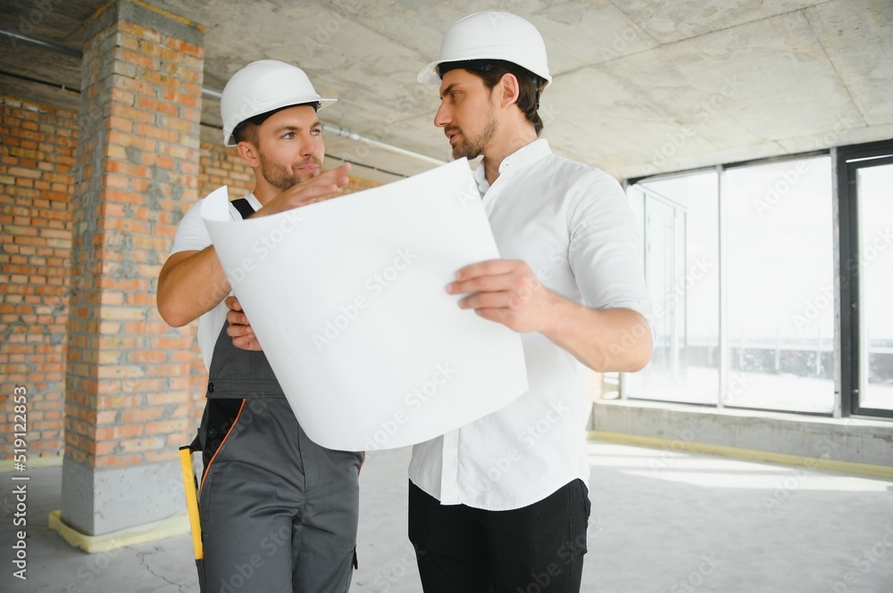 Male Architect Giving Instructions To His Foreman At Construction Site. Male Architect Giving Instructions To His Foreman At Construction Site.