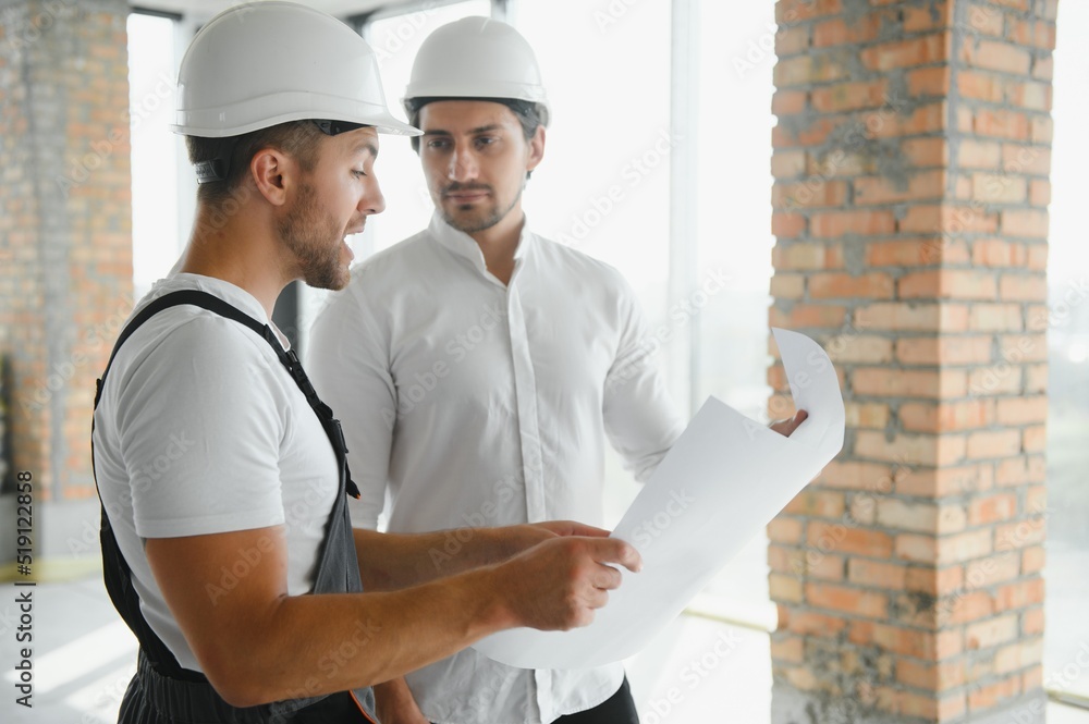 View of a Worker and architect watching some details on a construction View of a Worker and architect watching some details on a construction