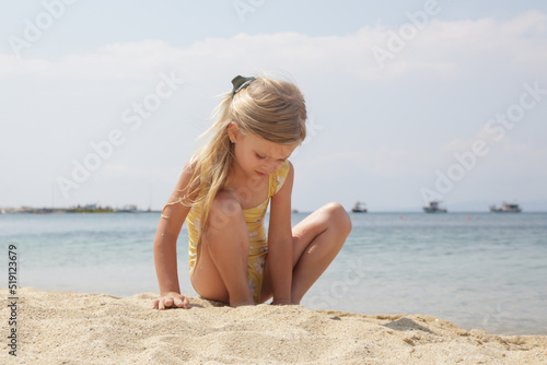 Little 4 years old girl playing on the sand beach