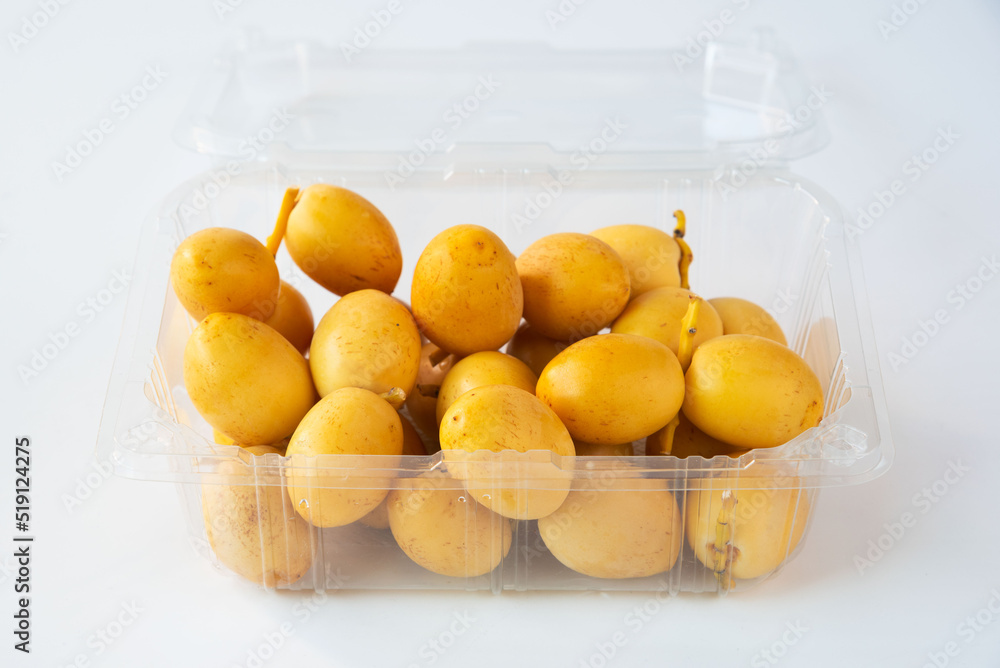 Fresh date palm fruit in plastic package on white background