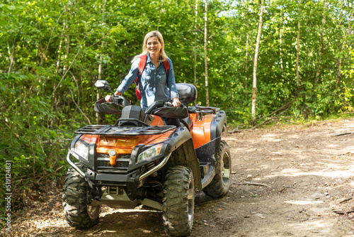 Young woman on quad bike on a trail. Young woman driving all terrain vehicle in nature on a sunny day
