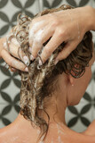 Young woman taking shower and washing her hair in shower cabine.