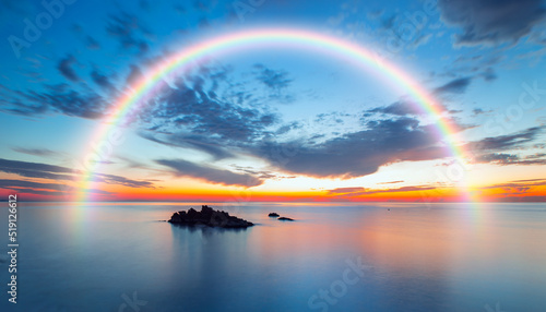 Long exposure image of dramatic sky and seascape with rock at sunset, Amazing rainbow in the background 