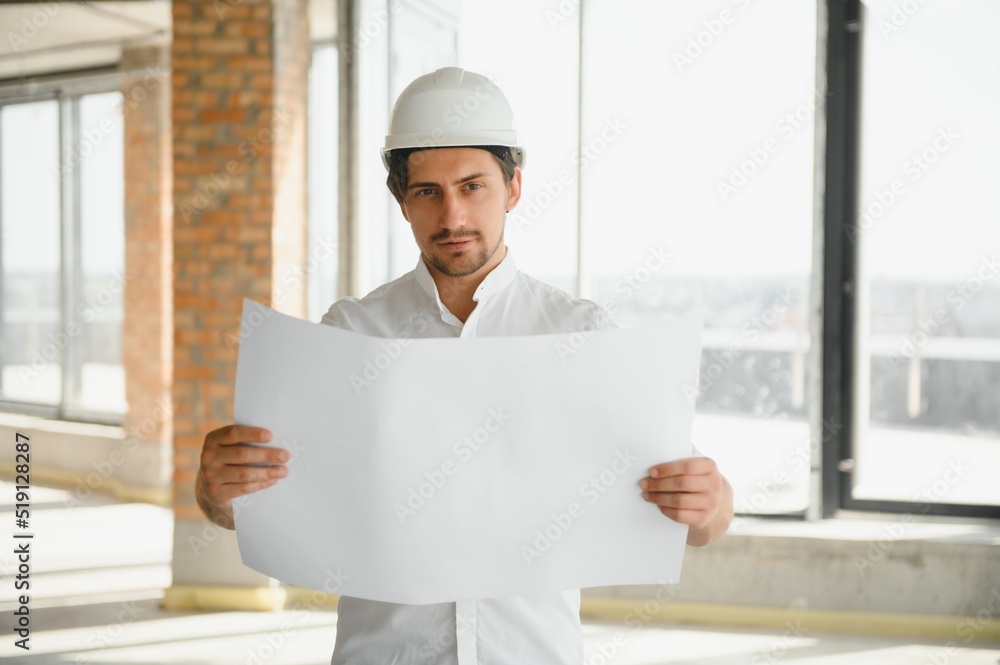 Portrait of an architect builder studying layout plan of the rooms, serious civil engineer working with documents on construction site, building and home renovation, professional foreman at work. Portrait of an architect builder studying layout plan of the rooms, serious civil engineer working with documents on construction site, building and home renovation, professional foreman at work.