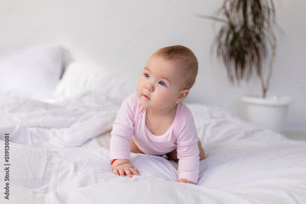 baby in a pink bodysuit is lying in a crib on snow-white bed linen, lifestyle