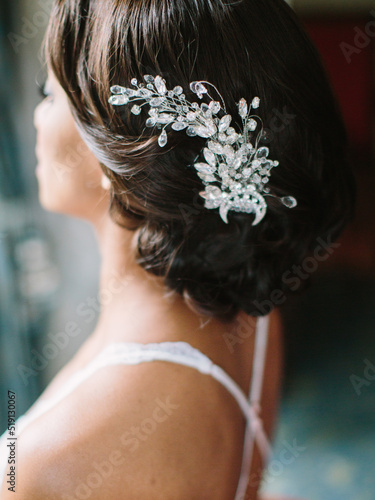 Wedding hairstyle of dark hair with a massive hairpin with white stones close-up.