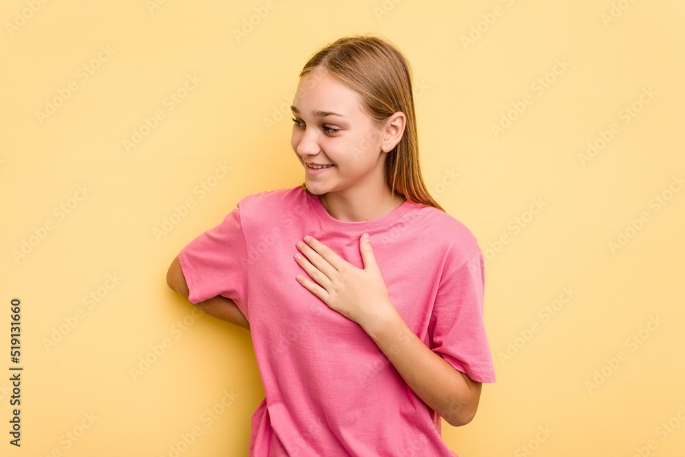 Young caucasian girl isolated on yellow background laughing keeping hands on heart, concept of happiness. Young caucasian girl isolated on yellow background laughing keeping hands on heart, concept of happiness.