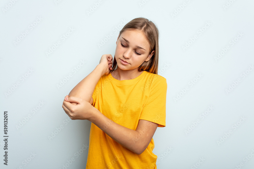Young caucasian girl isolated on blue background massaging elbow, suffering after a bad movement. Young caucasian girl isolated on blue background massaging elbow, suffering after a bad movement.