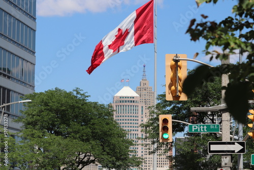 Canadian flag over city street lights and signs