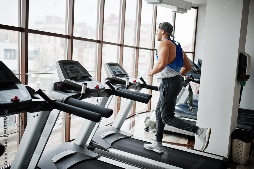Fit and muscular arabian man running on treadmill in gym. Fit and muscular arabian man running on treadmill in gym.