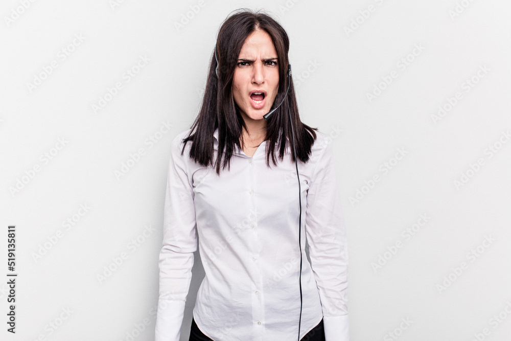 Telemarketer caucasian woman working with a headset isolated on white background screaming very angry and aggressive. Telemarketer caucasian woman working with a headset isolated on white background screaming very angry and aggressive.
