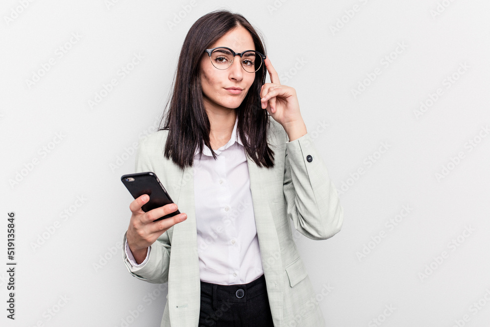 Young business caucasian woman holding mobile phone isolated on white background pointing temple with finger, thinking, focused on a task. Young business caucasian woman holding mobile phone isolated on white background pointing temple with finger, thinking, focused on a task.