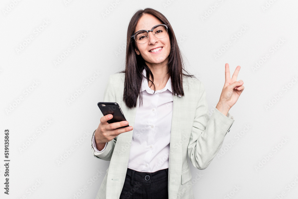 Young business caucasian woman holding mobile phone isolated on white background joyful and carefree showing a peace symbol with fingers.