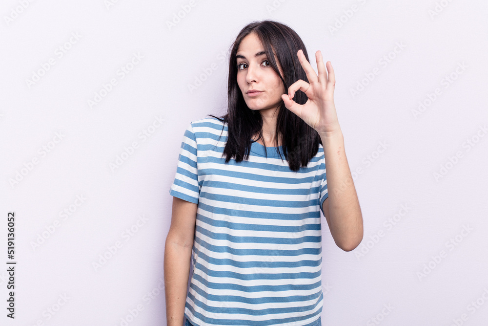 Young caucasian woman isolated on pink background winks an eye and holds an okay gesture with hand. Young caucasian woman isolated on pink background winks an eye and holds an okay gesture with hand.