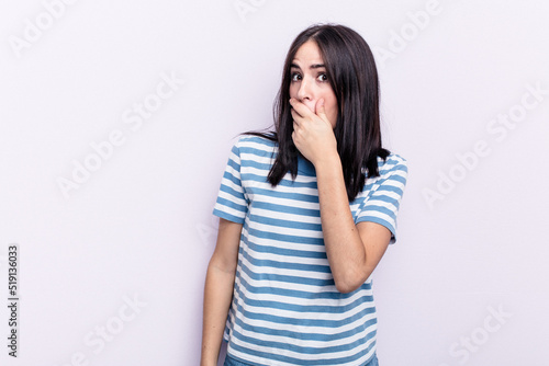 Young caucasian woman isolated on pink background covering mouth with hands looking worried.