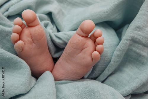 Baby's feet in close-up with empty space for text, copy space, on background of a green blanket, maternity, home birth, upbringing and care of the baby,  problem of abortion and surrogate motherhood