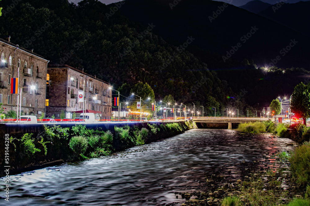 Obraz premium Night city from a bird's eye view. The light of houses and cars. A beautiful city with rivers, bridges and beautiful buildings. City among the mountains, Kapan, Armenia