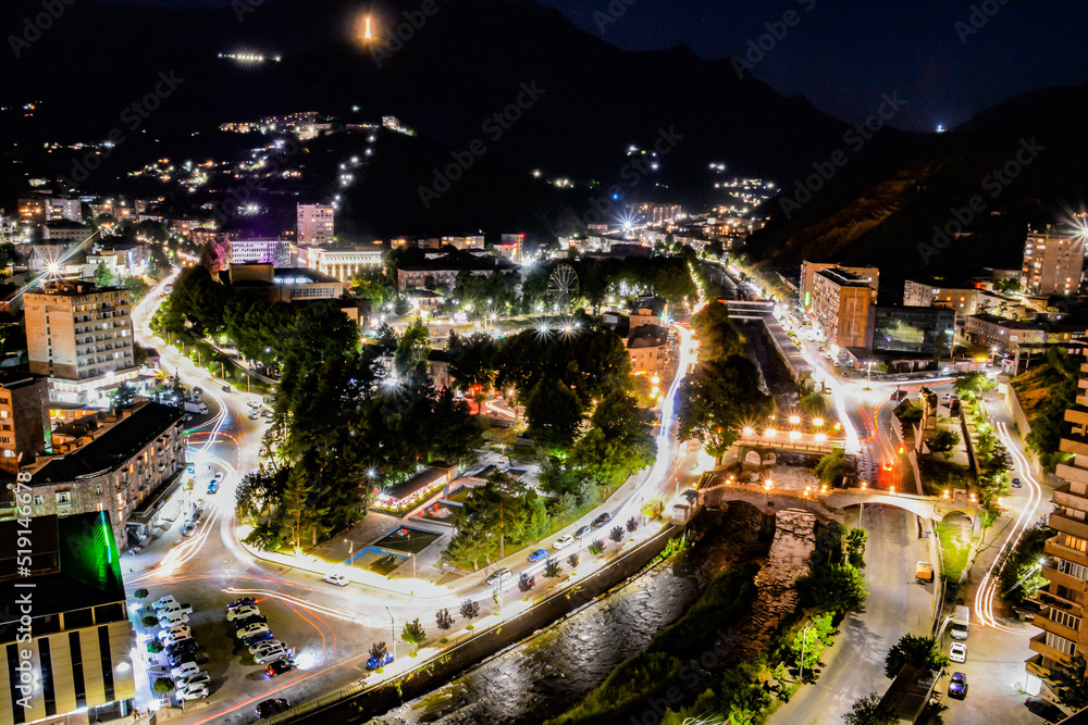 Fototapeta premium Night city from a bird's eye view. The light of houses and cars. A beautiful city with rivers, bridges and beautiful buildings. City among the mountains, Kapan, Armenia