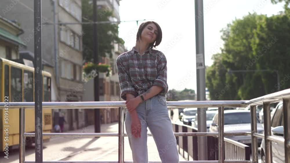 Portrait of beautiful cute young woman posing into the camera, standing along the road with taffic at the city Portrait of beautiful cute young woman posing into the camera, standing along the road with taffic at the city