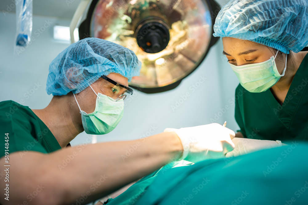 Asian Professional surgeons team performing surgery in the operating room, surgeon, Assistants, and Nurses Performing Surgery on a Patient, health care cancer and disease treatment concept Asian Professional surgeons team performing surgery in the operating room, surgeon, Assistants, and Nurses Performing Surgery on a Patient, health care cancer and disease treatment concept