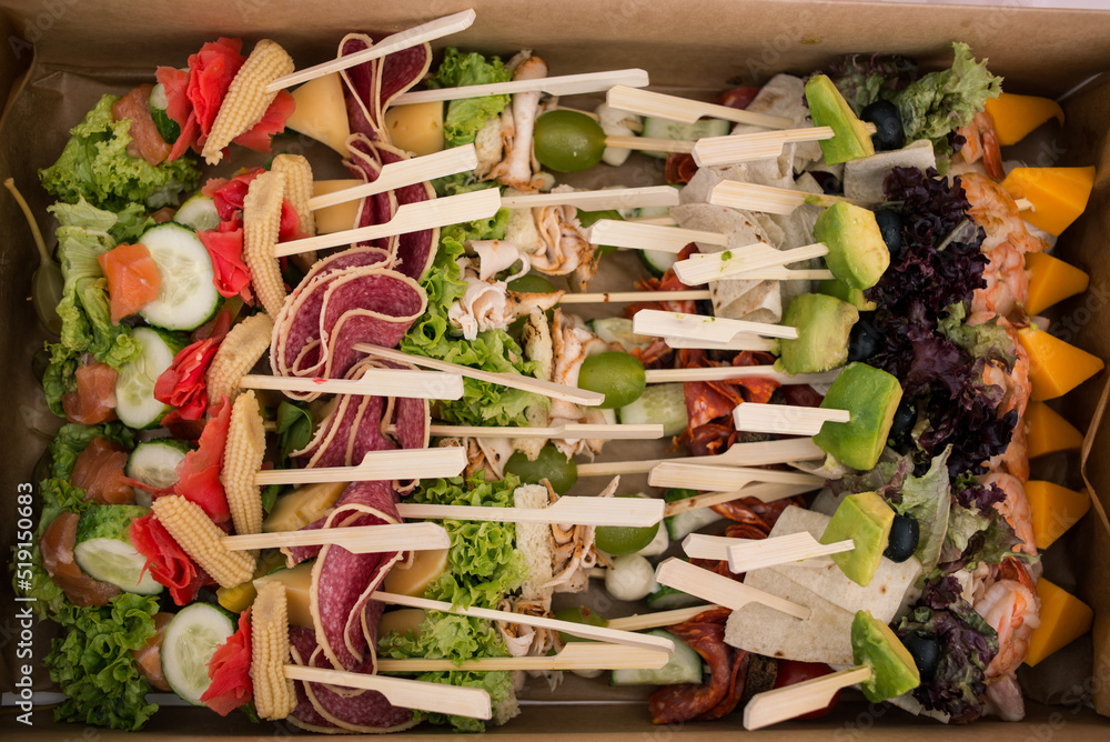 Delicious juicy catering in nature. Neatly folded skewers with sausage, cheese, cucumber and avocado for a hearty lunch. Fresh and delicious outdoor lunch