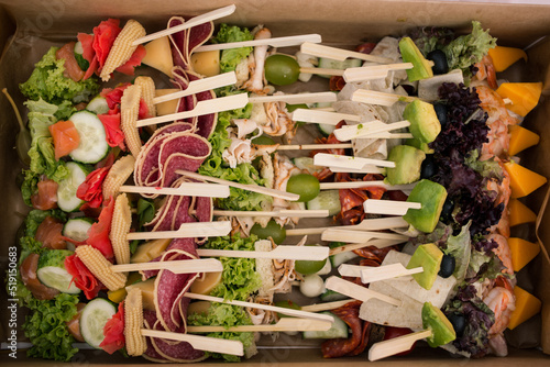 Obraz na płótnie Delicious juicy catering in nature. Neatly folded skewers with sausage, cheese, cucumber and avocado for a hearty lunch. Fresh and delicious outdoor lunch w salonie