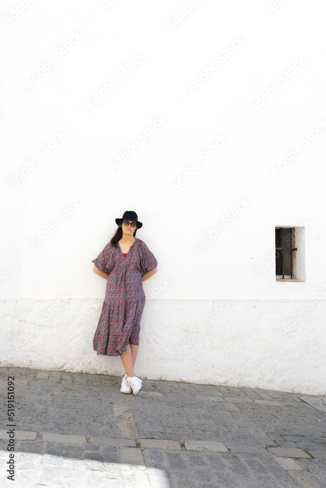 Standing Unrecognizable woman with a black hat and sunglasses in a white street in Andalusia, Spain 