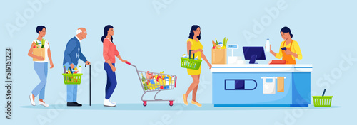 Customers stand in line at grocery supermarket with goods in shopping trolley. Woman put buys on cashier desk for paying. Queue in Store. Grocery Purchases