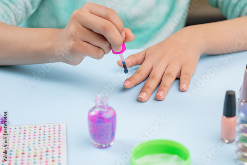 Teenage woman painting her nails at home  with nail supplies on the table