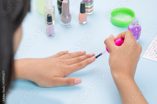 Hands of a young woman painting her nails with a varnish  and nail accessories on the table