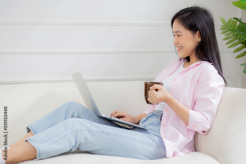 Young asian business woman work from home with laptop computer and drinking coffee on sofa in living room, freelance girl using notebook sitting on couch with comfort and relax, lifestyles concept. Young asian business woman work from home with laptop computer and drinking coffee on sofa in living room, freelance girl using notebook sitting on couch with comfort and relax, lifestyles concept.