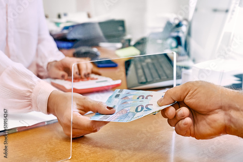 фотографія Hand of female social worker taking or giving euro money from client at office workplace with plexiglass separator