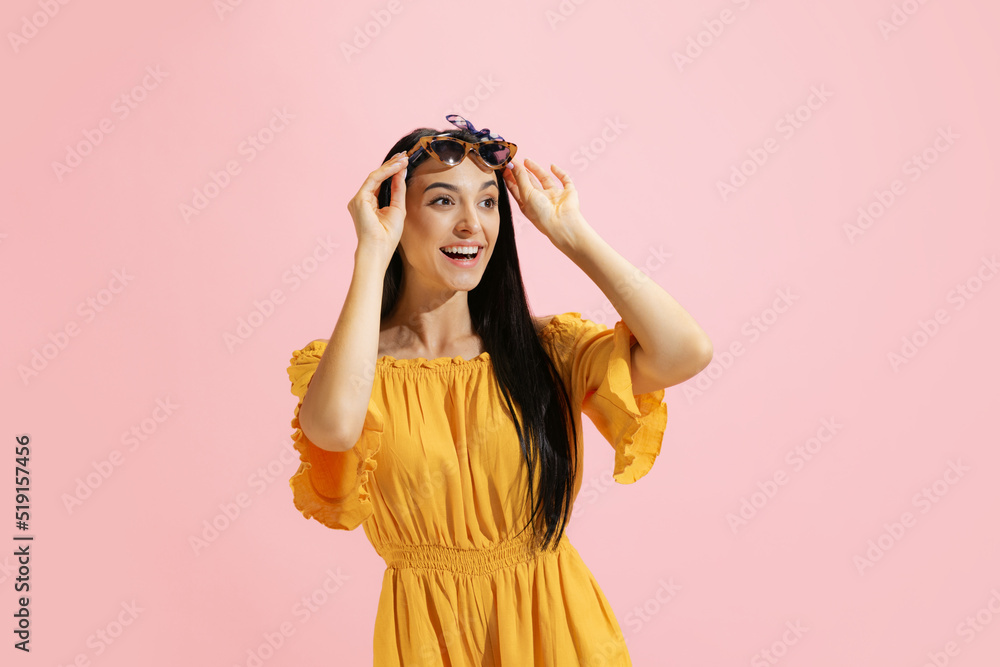 Portrait of young beautiful girl, student in summer yellow dress isolated on pink background. Concept of beauty, art, fashion, human emotions Portrait of young beautiful girl, student in summer yellow dress isolated on pink background. Concept of beauty, art, fashion, human emotions
