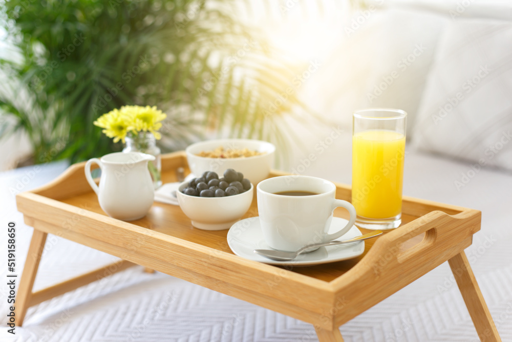 Wooden tray with breakfast on the bed