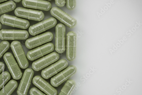 Green powder capsules Superfood. Place for text. Spirulina, chlorella capsules