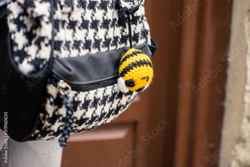 Cute handmade or knitted and stuffed bee hanged as keyring on a backpack for kids. Small amigurumi funny animal as souvenir photo