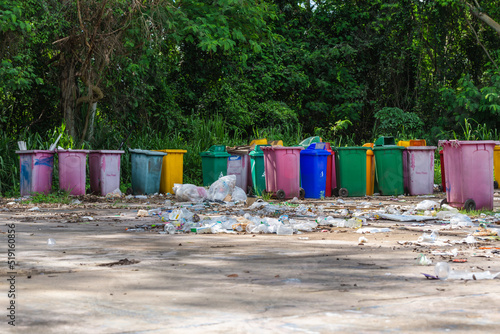 Several plastic bins are left in the garbage collection area, causing pollution.