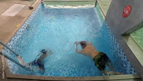 Port Dickson, Malaysia December 17, 2020 Father and son swimming together in a private pool in Lexis Hibiscus Hotel Resort, Negeri Sembilan. photo