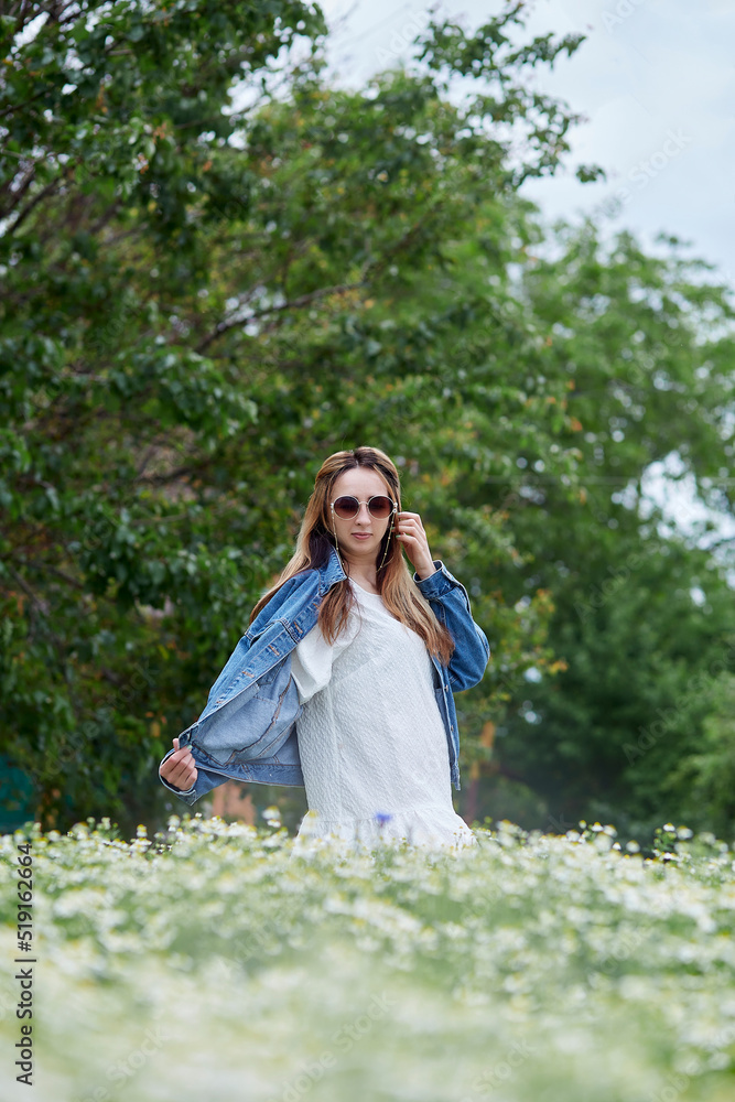 Stylish elegant millennial girl in chamomile field relaxing. Connecting with nature. Summertime aesthetic Stylish elegant millennial girl in chamomile field relaxing. Connecting with nature. Summertime aesthetic