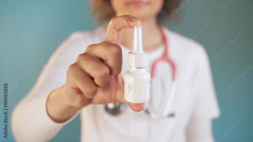 Woman doctor shows a medical product for the nose. The young doctor stands in the blue background Woman doctor shows a medical product for the nose. The young doctor stands in the blue background