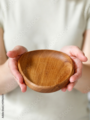 Empty oval wooden oak plate, dish in woman hands. Empty and template mockup with place for food. Kitchen utensils.
