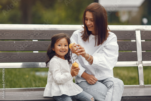 Mother with daughter eats ice cream in the city