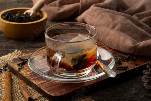 Black tea,Tea bag in hot water in glass cup on wooden table photo
