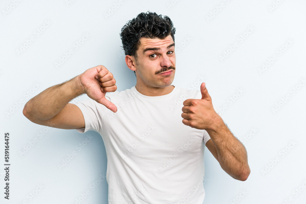 Young caucasian man isolated on blue background showing thumbs up and thumbs down, difficult choose concept Young caucasian man isolated on blue background showing thumbs up and thumbs down, difficult choose concept