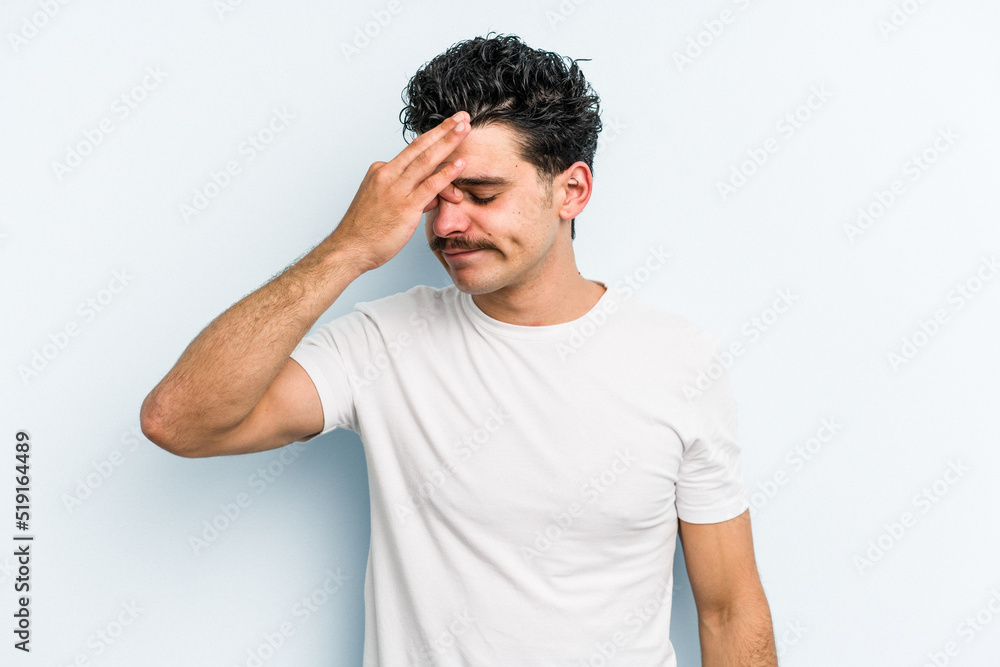 Young caucasian man isolated on blue background having a head ache, touching front of the face. Young caucasian man isolated on blue background having a head ache, touching front of the face.